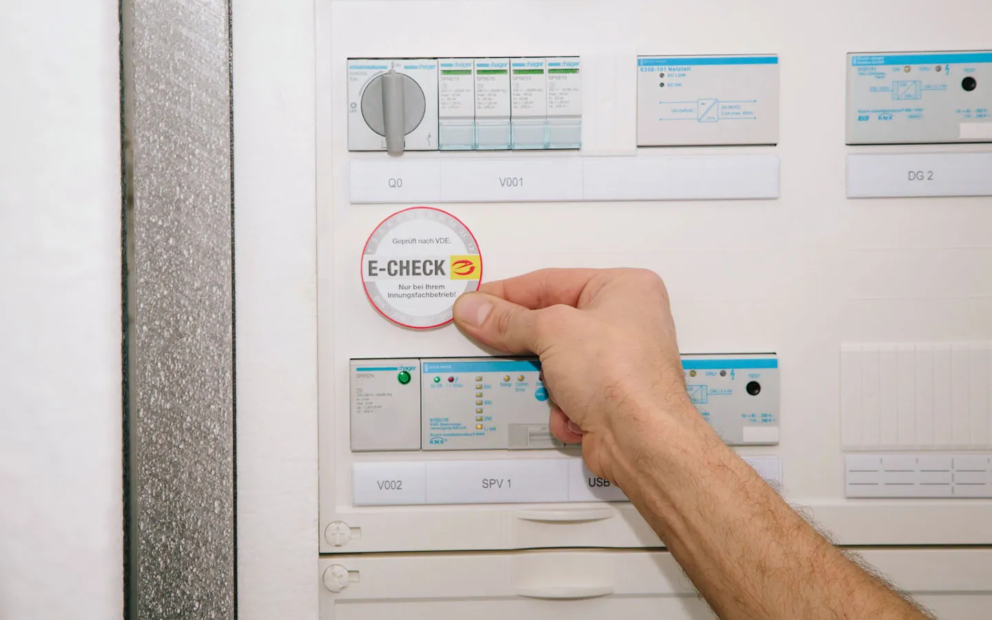 E-CHECK - Mitarbeiter klebt in der Verteilung die E-CHECK Plakette an &middot; Elektro-Stock