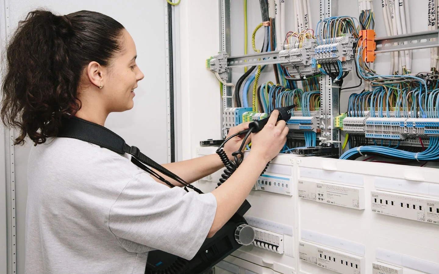 E-CHECK - Mitarbeiterin prüft im Schaltschrank mit einem Meßgerät &middot; Elektro-Stock